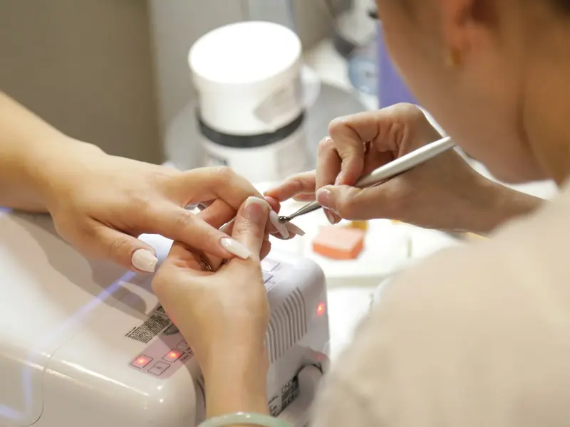 Prothésiste ongulaire travaillant sur les ongles d’une cliente