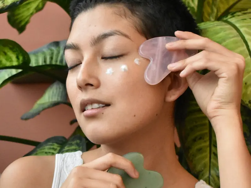 Femme passant une pierre de gua sha sur sa joue