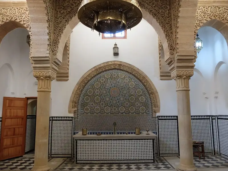Salle de hammam carrelée sous des arcs sculptés