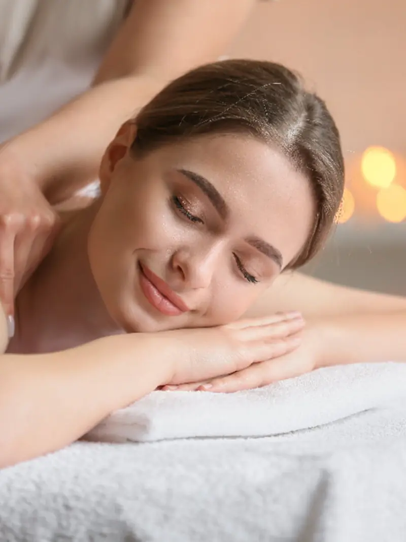 Massage du dos sur linge blanc, dans une lumière chaude